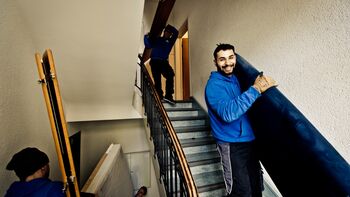 Mitarbeiter tragen Möbel von Wohnungsauflösung das Treppenhaus herunter