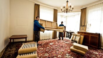 Mitarbeiter tragen auseinandergebautes Sofa aus einer Nachlassauflösung